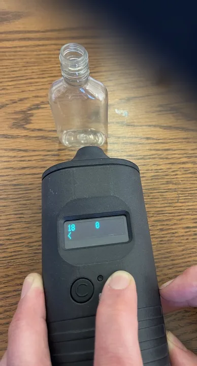 A handheld reader beside an untagged 50 mL plastic bottle, reading zero
